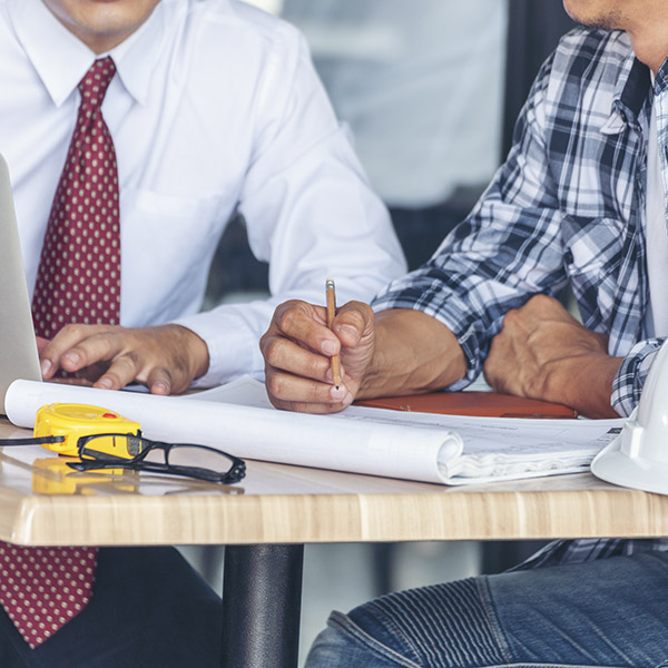 Contractor construction engineer meeting together on architect table at construction site. Business man and engineer manager discussing with foreman team builder blueprint planning design paperwork.