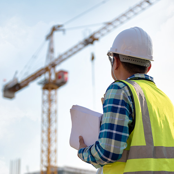 Engineering Consulting people on construction site holding blueprint in his hand and control workflow of the new building.