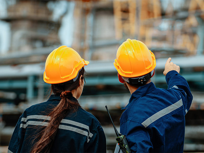Two workers in safety helmets inspecting an industrial facility.