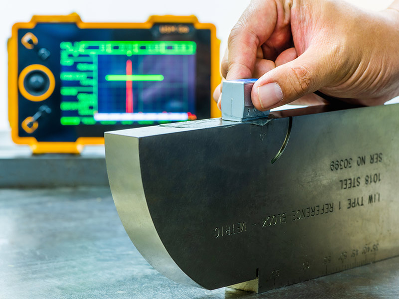 Technician performing ultrasonic inspection on a metal component.